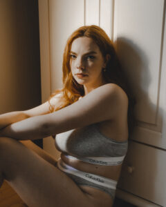 A woman sitting on the floor wearing Calvin Klein underwear.
