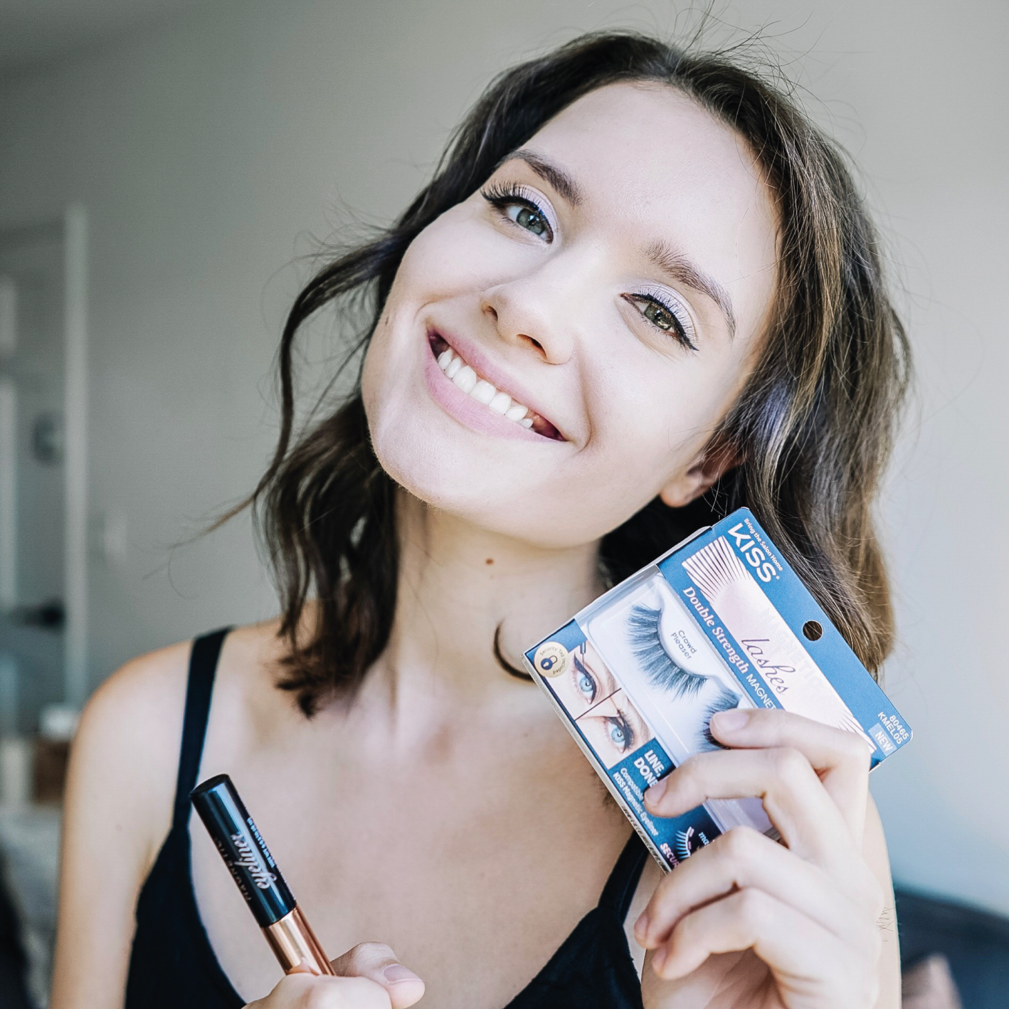 TikTok Shop – Going Live_2 A smiling woman showcasing makeup products from Kiss Cosmetics.