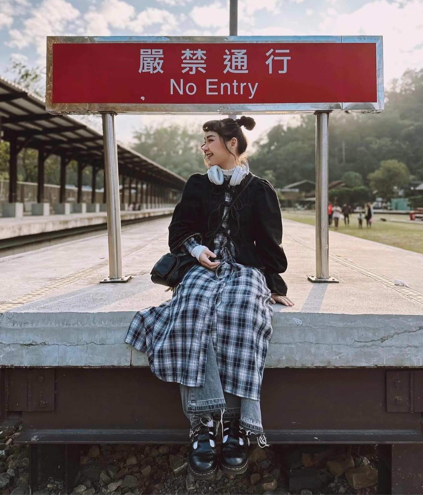 Girl sitting in a train station, smiling and showing her outfit.