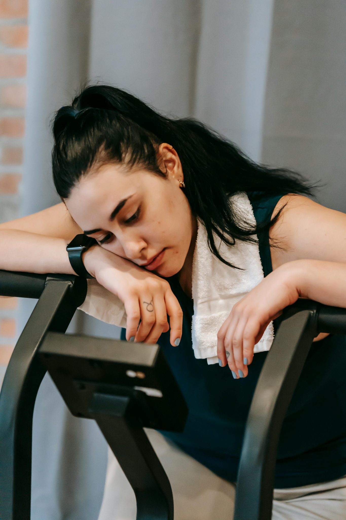 ired woman in workout gear resting her head on gym equipment, representing creator burnout from repetitive one-off brand campaigns